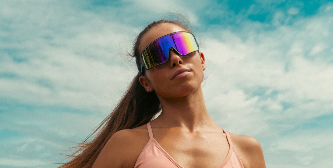 Woman wearing Mattingly wraparound sunglasses with mirrored lenses under a partly cloudy sky