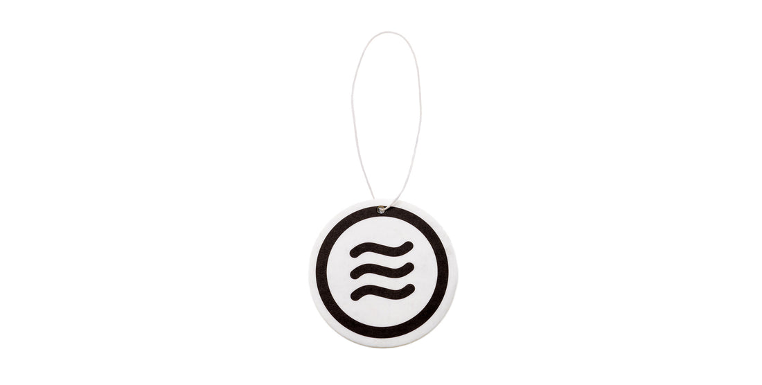 View of Signature Air Freshener showcasing black Neven tilde logo on a 2.5-inch white round disc with hanging string