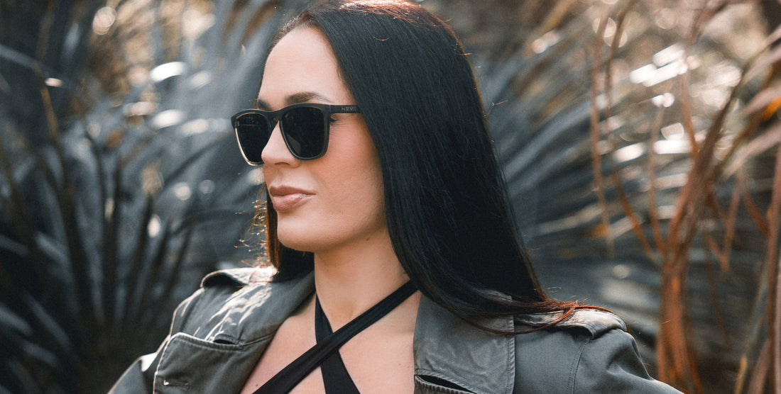 Woman wearing Fir olive green rectangular polarized sunglasses in a sunlit outdoor setting with leafy background