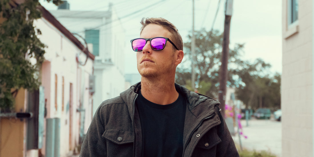 Man wearing Violet rectangular sunglasses with deep purple lenses and bold black frames on a city street