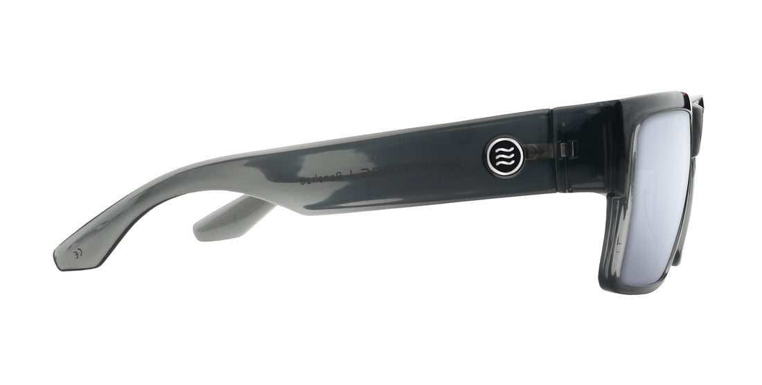 Side view of Banshee sunglasses showcasing thick transparent gray temple with round Neven logo and silver mirrored lens on white background