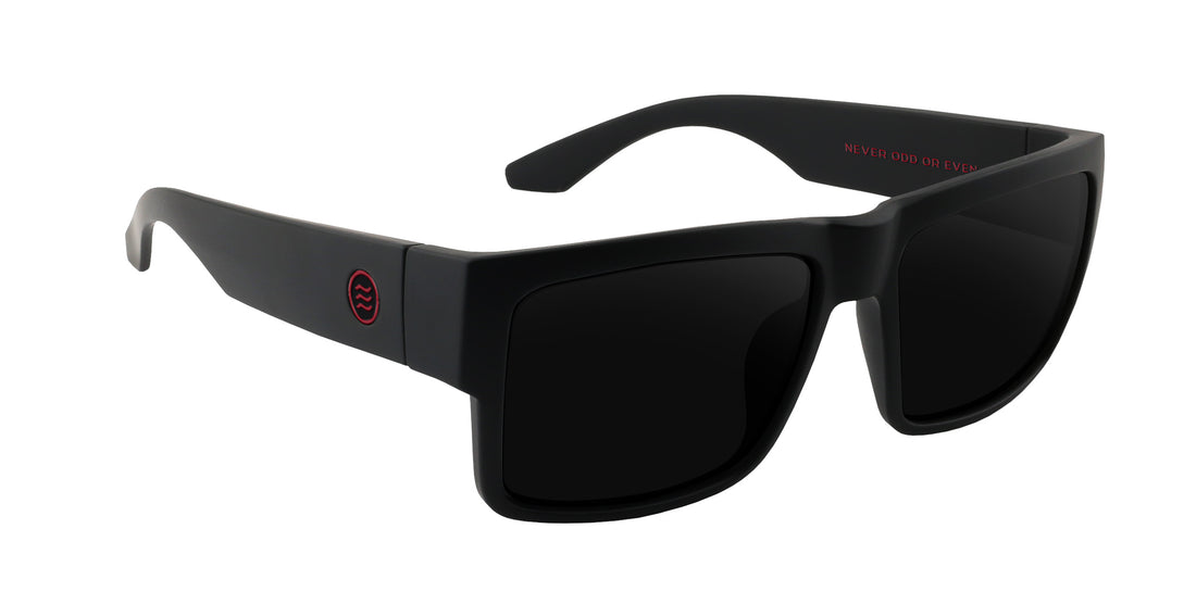 Close-up of Havoc Rx sunglasses, matte black square frame, dark prescription lenses, red temple logo on white