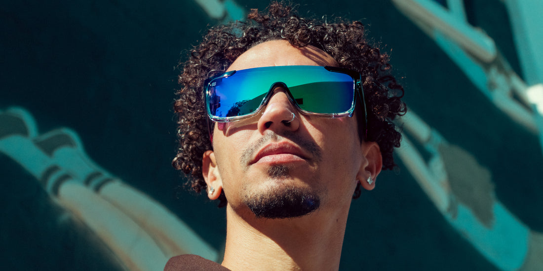 Man wearing Night Watch shield-style polarized sunglasses in front of a colorful mural