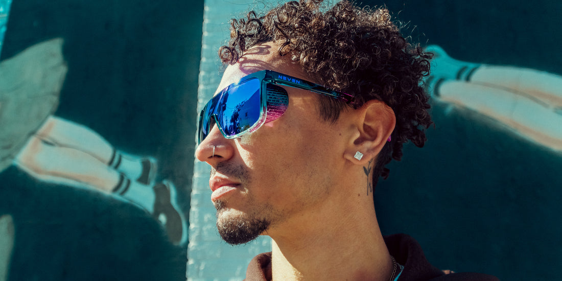 Man wearing Night Watch shield sunglasses with mirrored blue polarized lenses and removable side shields in front of a mural