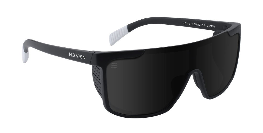 Three-quarter view of Pitch Black sunglasses showing wraparound polarized lens and removable side shields on matte black frame with white temple tips