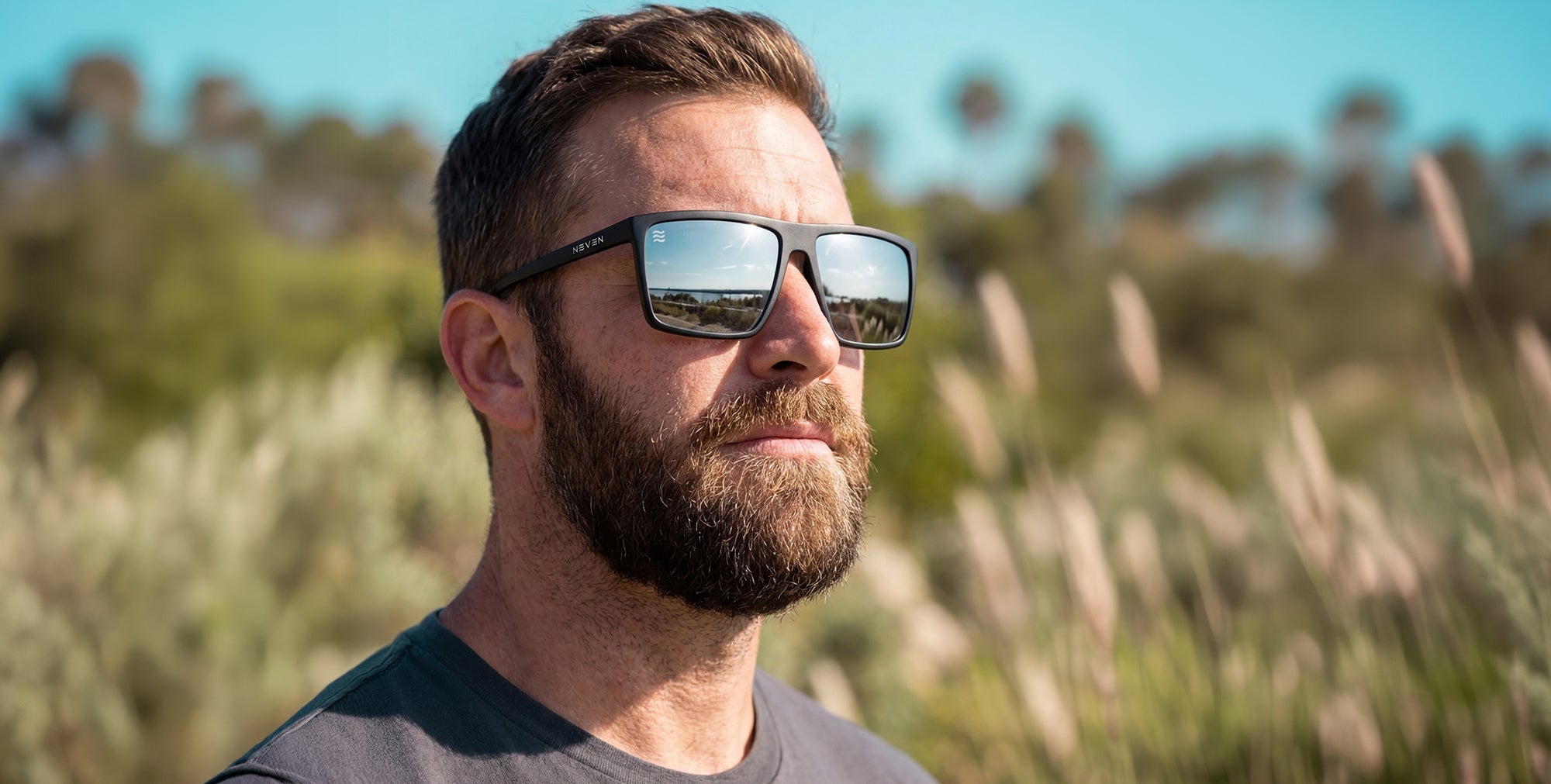 Man wearing sunglasses with a natural background of trees and grass