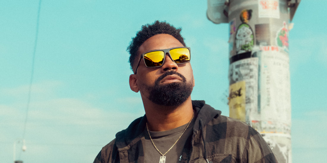 Man wearing Norton polarized sunglasses looking up against a clear blue sky, black frame with yellow mirrored lenses