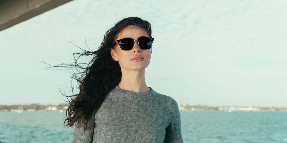 Woman wearing Bullet black semi-rimless polarized sunglasses standing on a boat with windblown hair and ocean background