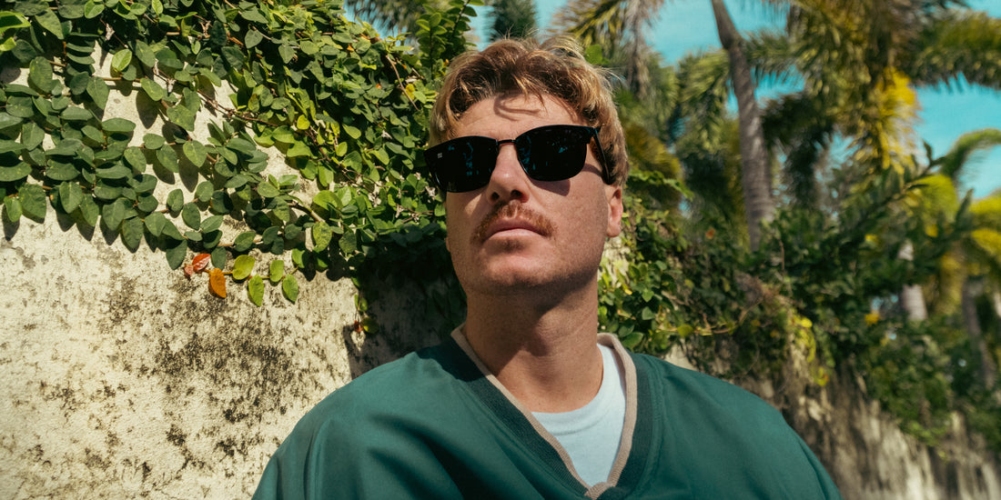 Man wearing black polarized Stealth sunglasses in a sunny tropical garden