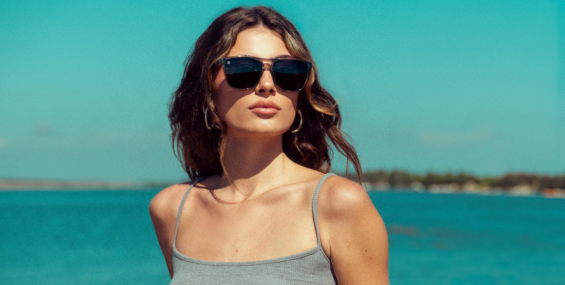 Woman wearing Rip Tide transparent gray sunglasses with black polarized lenses at a sunny beach