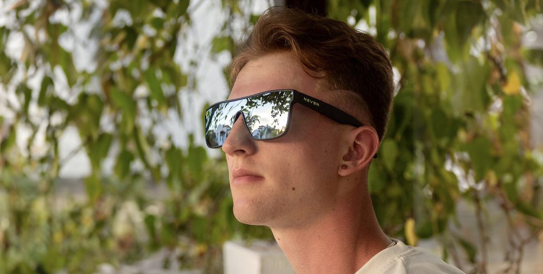 Model wearing black CJ polarized sunglasses with silver lenses outdoors among greenery