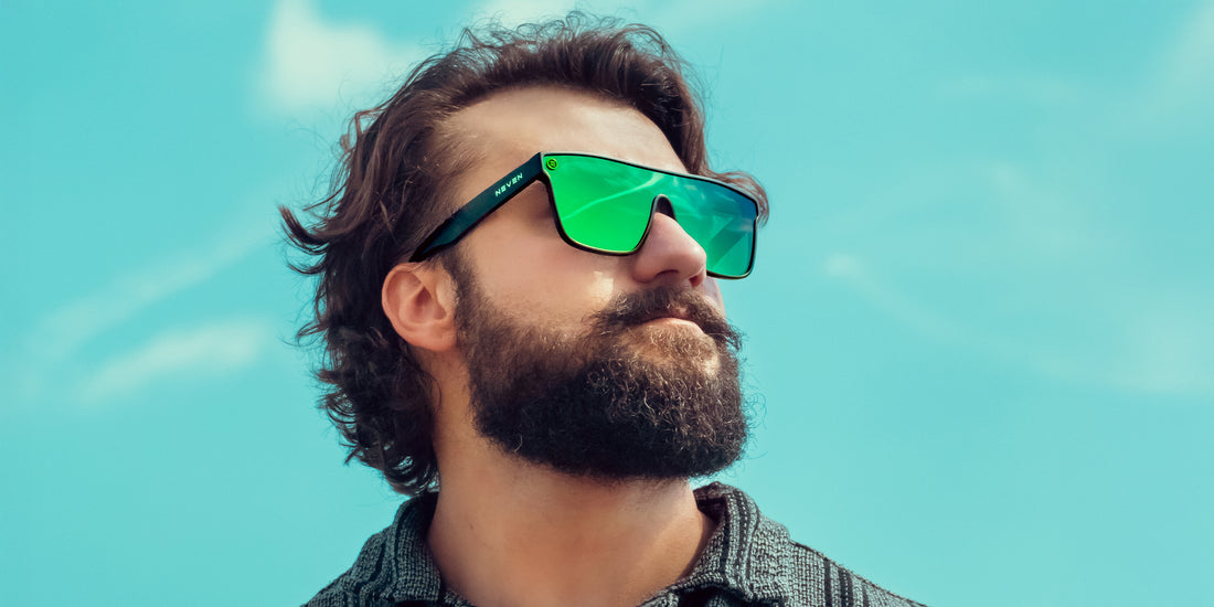 Bearded man wearing matte black Lucky XL polarized shield sunglasses with green mirrored lenses against a bright blue sky