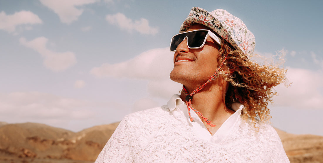 Woman wearing white Permafrost rectangular polarized sunglasses outdoors with mountains in the background