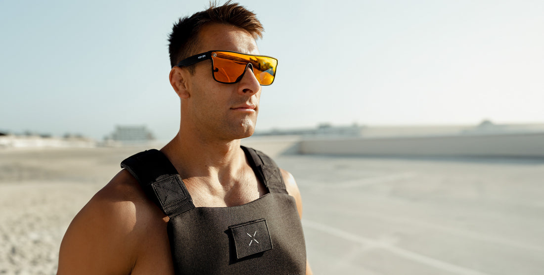 Side view of Zero Cool sunglasses showing red-orange polarized uni-lens and black frame with Neven logo on a sunny beach