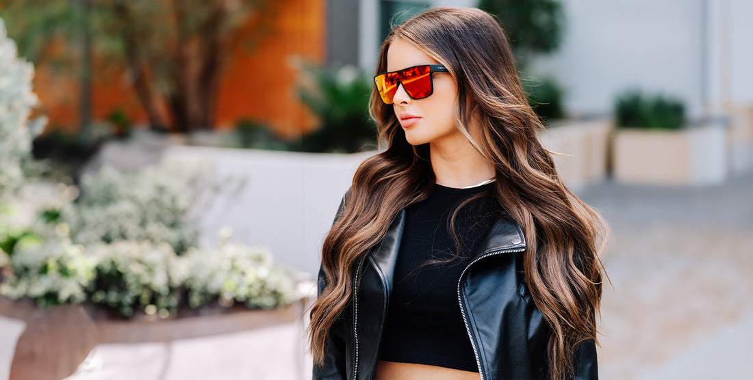Model wearing Zero Cool polarized red-orange uni-lens sunglasses with black frame in an outdoor urban setting