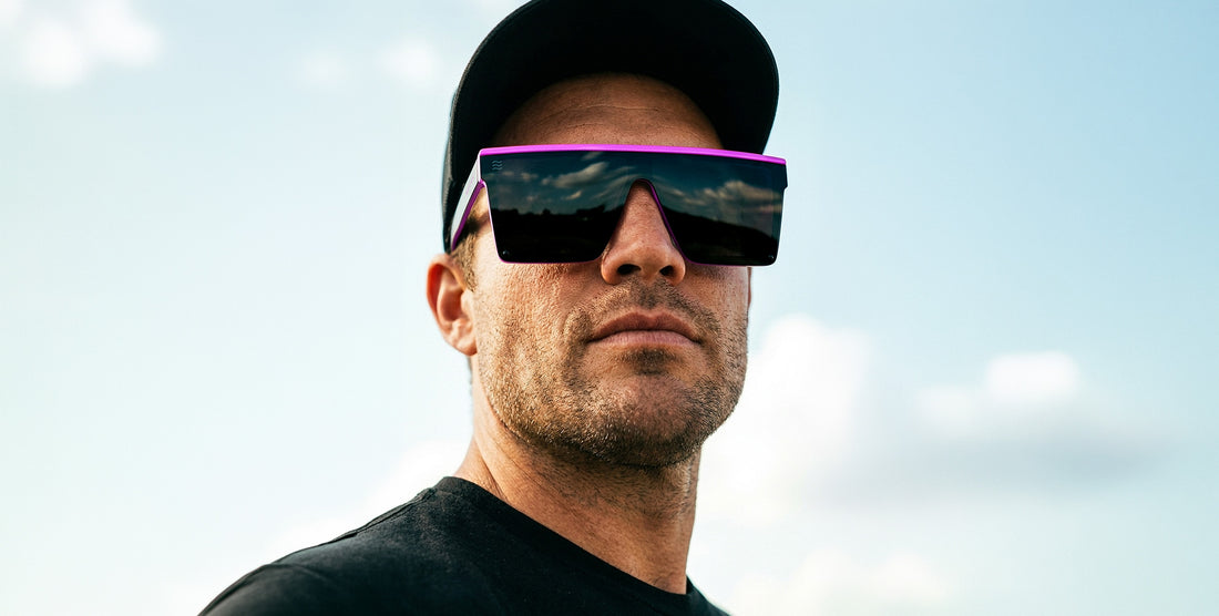 Close-up of Never Enough polarized sunglasses showing oversized pink-accent shield lens worn by a man against a blue sky
