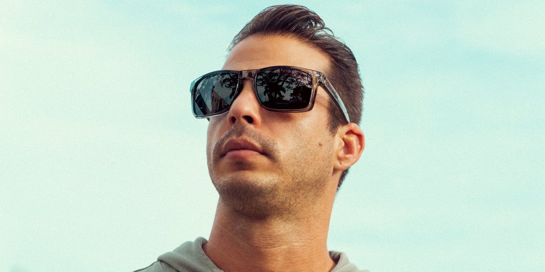 Close up of man wearing Breakers XL sunglasses with glossy gray squared frames and black polarized lenses against blue sky
