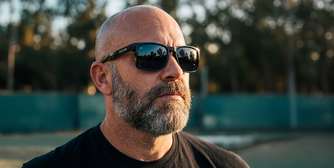 Close-up of Doom XL sunglasses on a model showing black frame, polarized lenses and oversized fit against blurred trees