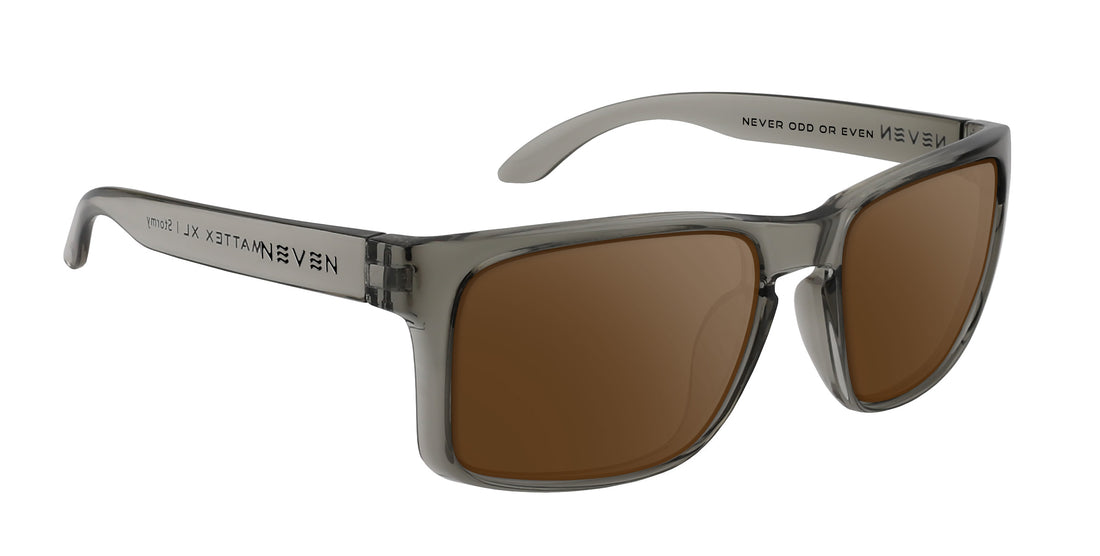 Three-quarter close-up of Stormy XL sunglasses showcasing transparent gray glossy oversized rectangular frame and brown prescription lenses on white background