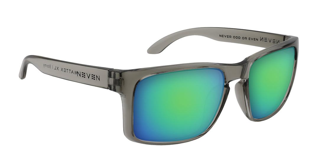 Angled close-up of Stormy XL sunglasses showing transparent gray oversized frame and green mirrored prescription lenses