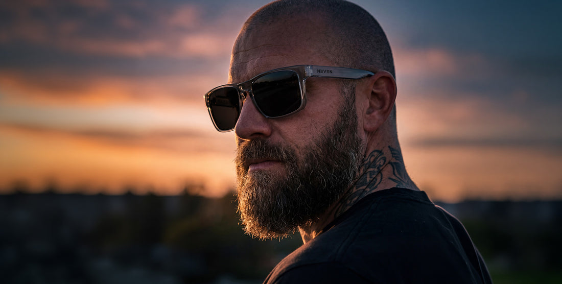 Side view of Breakers sunglasses on a model showcasing transparent gray rectangular frame and black polarized lenses against a sunset sky
