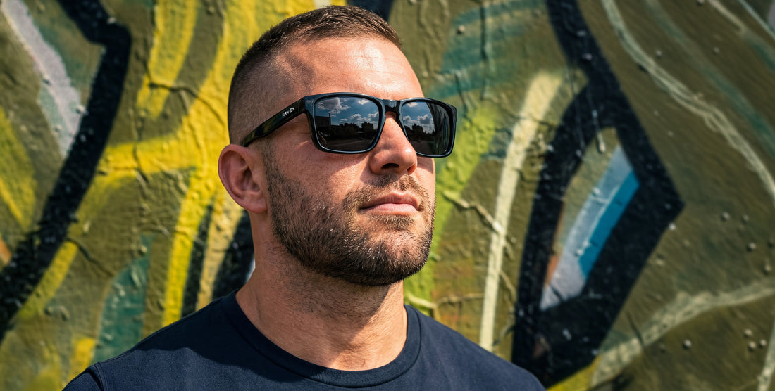 Man wearing Doom black polarized sunglasses against a colorful graffiti wall