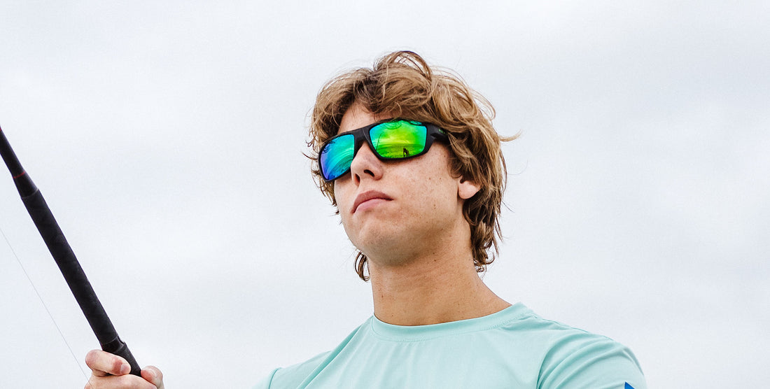 Young man wearing P. Steele black polarized sunglasses with green mirrored lenses while fishing on an overcast day