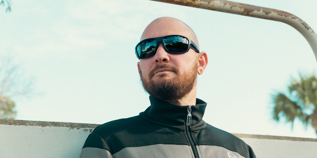 Close up of Raritan sunglasses showcasing black wraparound polarized lenses on a male model with pale sky background