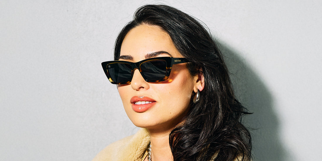 Woman wearing Dusk polarized sunglasses with a glossy black and tortoise frame against a gray background