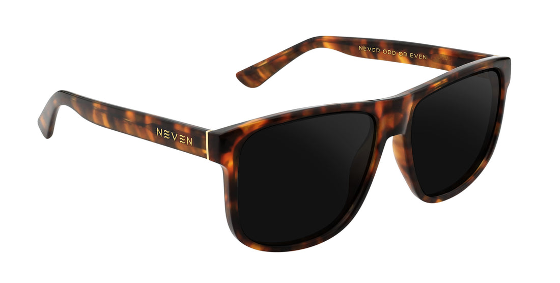 Three-quarter view of Ember prescription sunglasses with large tortoise shell frame, black lenses and gold accents on white
