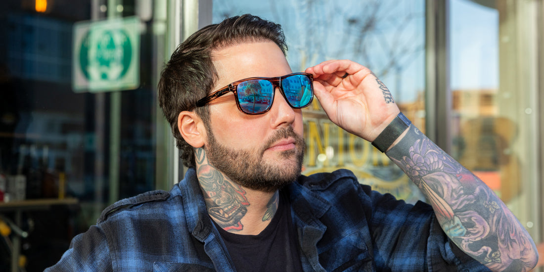 Man adjusting Solana sunglasses with blue lenses outside a storefront