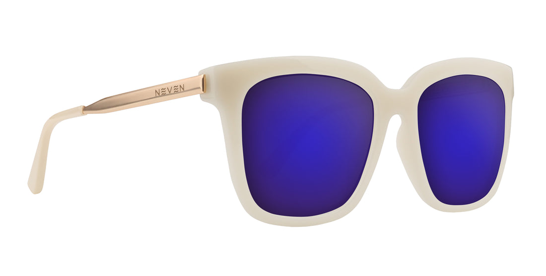 Close-up of Sand Dollar sunglasses with milky greige frame, gold engraved arms, and purple lenses on white background