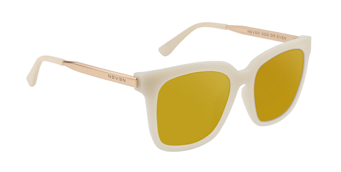 Three-quarter view of Sand Dollar prescription sunglasses showing milky white greige frame, gold engraved metal arms and yellow lenses on white background