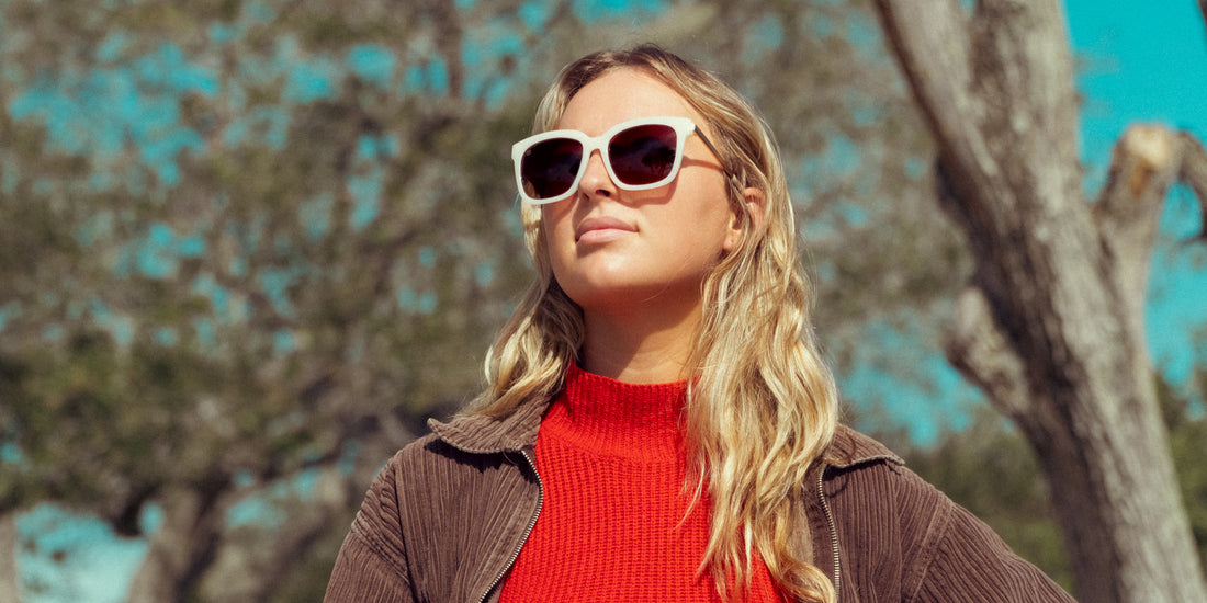 Woman wearing oversized Sand Dollar Beige Cat Eye polarized sunglasses outdoors among trees