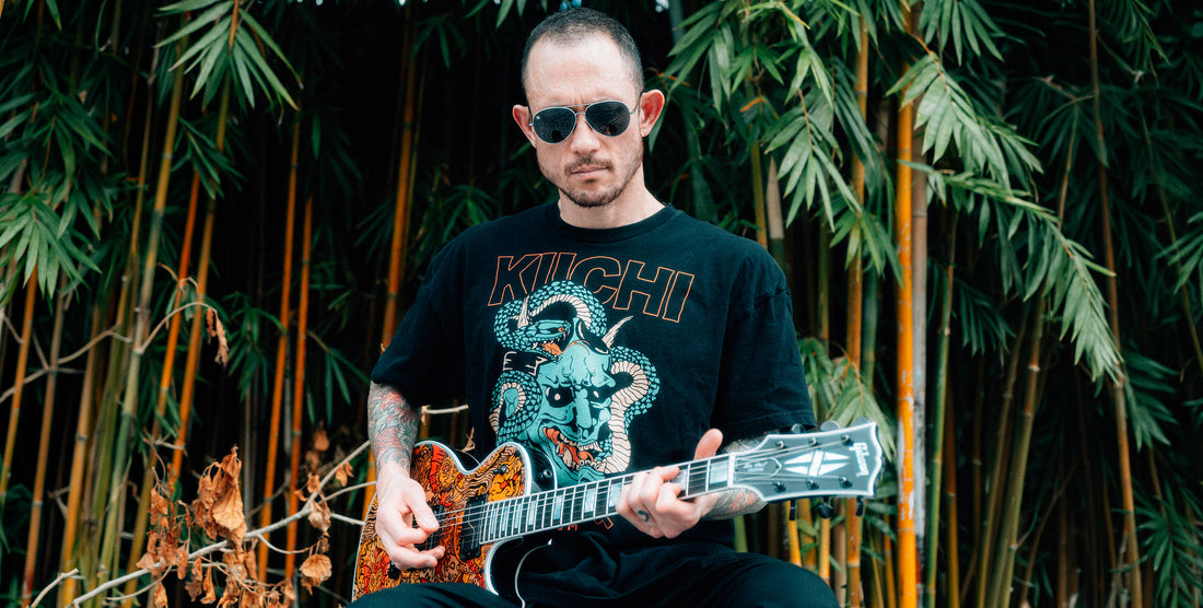Man wearing Shirogane silver aviator polarized sunglasses playing electric guitar seated in front of bamboo