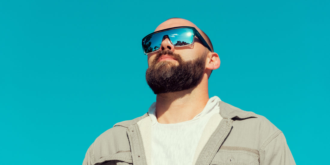 Bearded man wearing black rectangular polarized Inlet sunglasses looking up against a clear blue sky