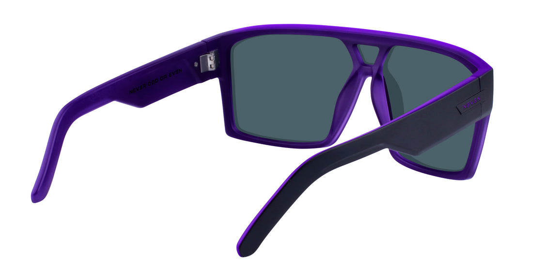 Close up three quarter view of Paradise sunglasses showcasing matte black exterior, purple inner frame and lenses and stainless steel hinge on white background