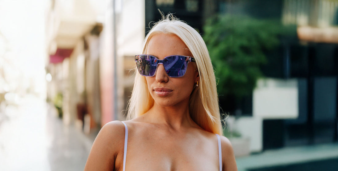 Woman wearing purple cat-eye polarized Discovery sunglasses walking on a sunlit city street