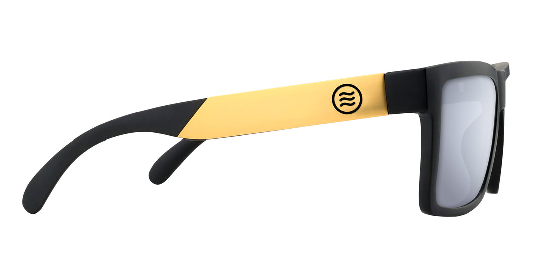 Side close-up of Prospector XL sunglasses with black matte frame, gold temple and wavy logo, Rx silver lens on white background
