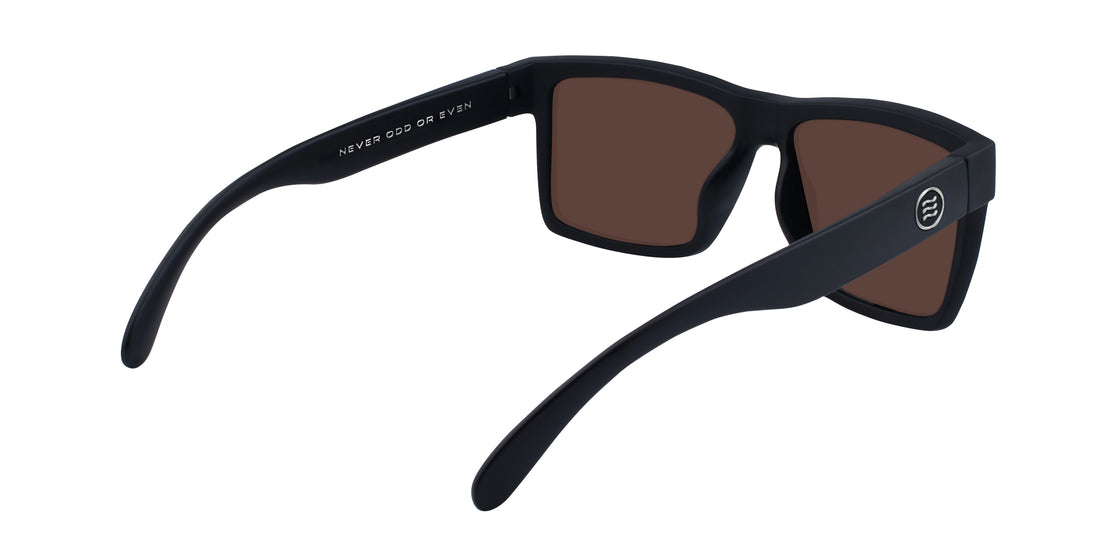 Three-quarter rear view of Montauk sunglasses showcasing matte black frame, brown polarized lenses, and round temple logo on white background