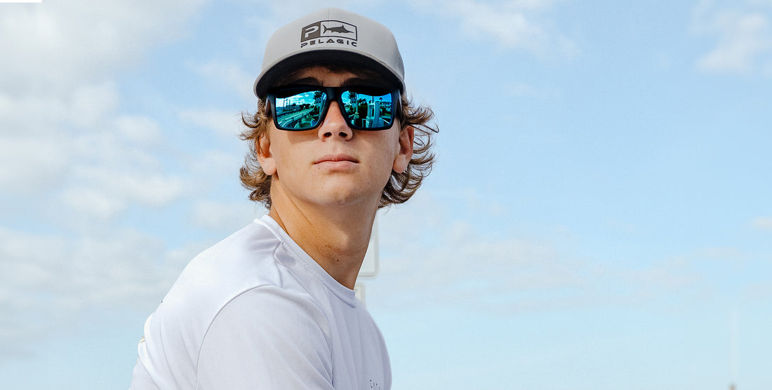 Man wearing Montauk black sunglasses with blue mirrored lenses looking toward the horizon against a blue sky