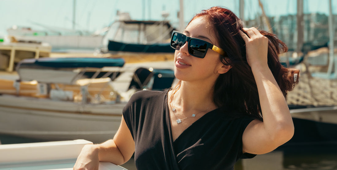 Woman wearing Prospector black polarized sunglasses with gold accents on a boat at a marina