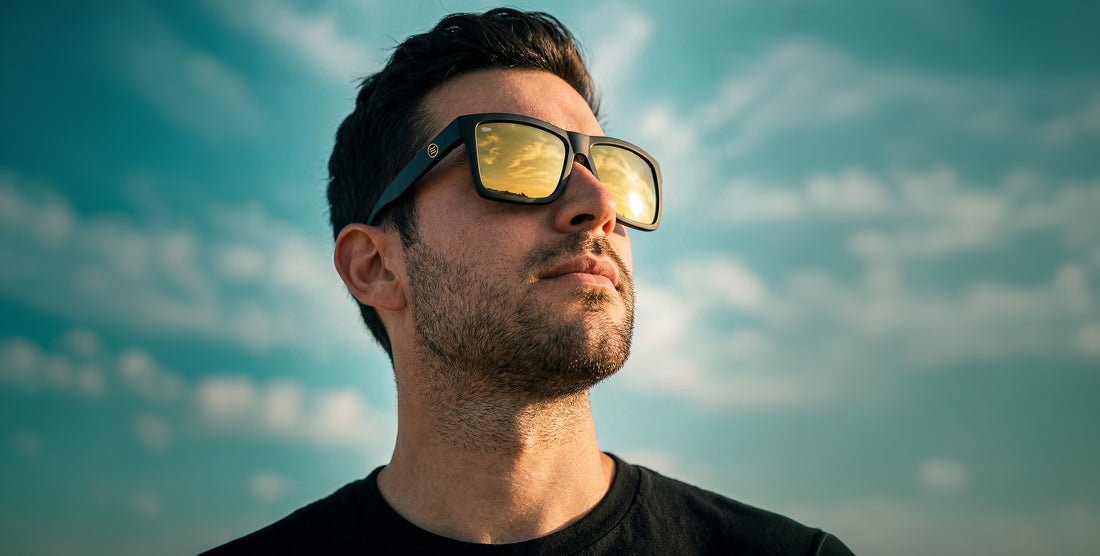 Man wearing Sentry sunglasses looking up toward sky, matte black frame with gold polarized mirrored lenses