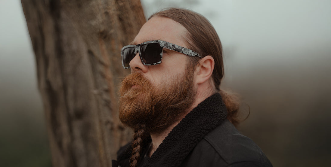 Man wearing South Shore sunglasses with greyscale camo TR90 frames and polarized lenses by a tree in a foggy coastal setting