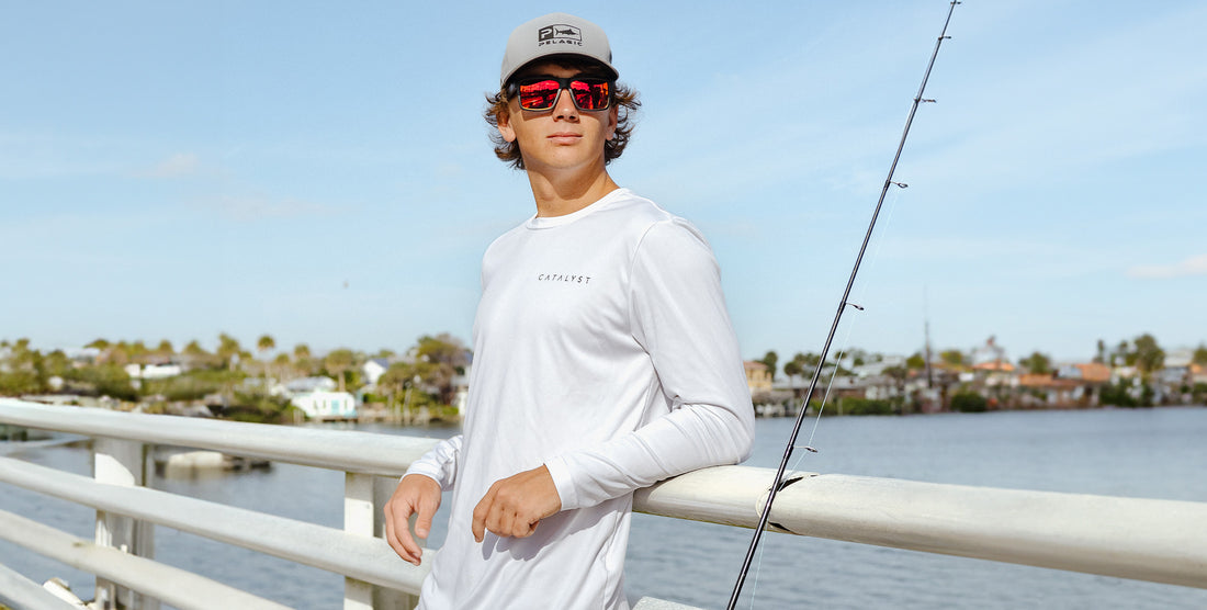 Young man fishing on a bridge wearing Supernova matte black sunglasses with red mirrored polarized lenses