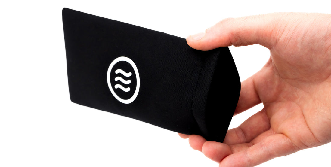 Angled close-up of Quick Close Case showcasing black color, Neven tilde logo, and a hand squeezing the quick-close opening